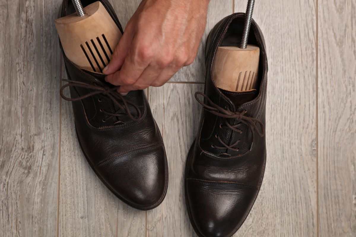 mano che infila strumento nelle scarpe per allargarle