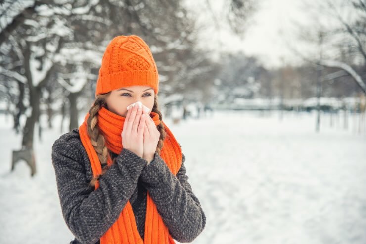 donna nella neve con sciarpa e cappello