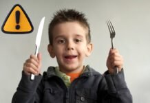 bambino con posate e segnale pericolo