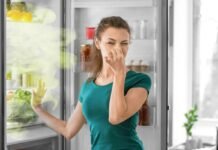 donna che si tappa il naso per i cattivi odori che escono dal frigo