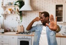 uomo in cucina che si tappa il naso per il cattivo odore