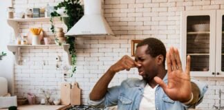 uomo in cucina che si tappa il naso per il cattivo odore