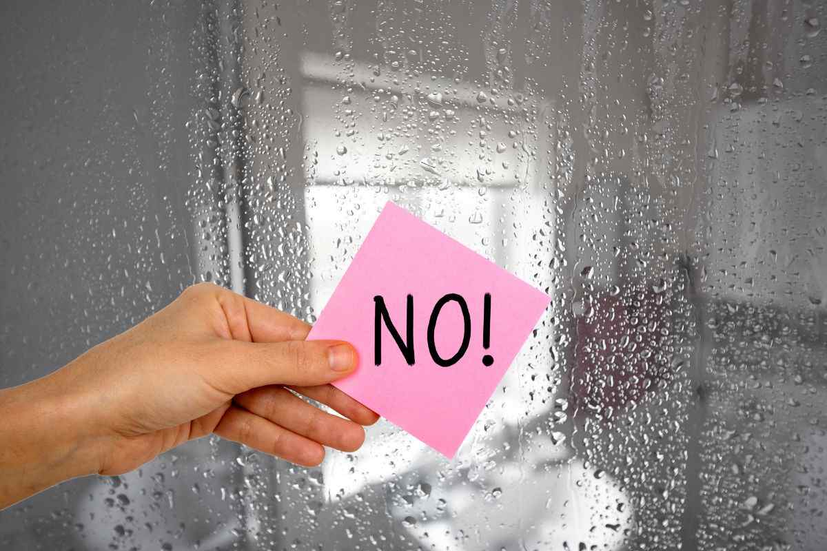 calcare sui vetri della doccia e mano con bigliettino su cui è scritto no