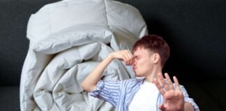 trapunta bianca arrotolata e uomo che si tappa il naso