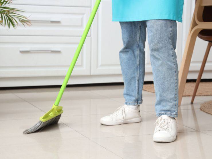 persona che sta passando scopa sul pavimento