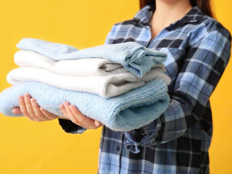 donna che mantiene diversi maglioni piegati