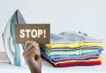 mano che mantiene un cartello con scritta stop e ferro da stiro con capi appena stirati