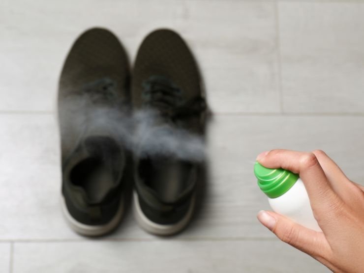 persona che spruzza spray sulle scarpe